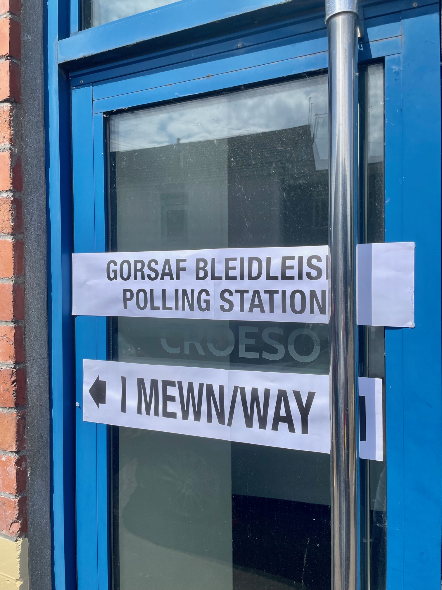 Bilingual sign indicating entrance to a polling station in Wales.